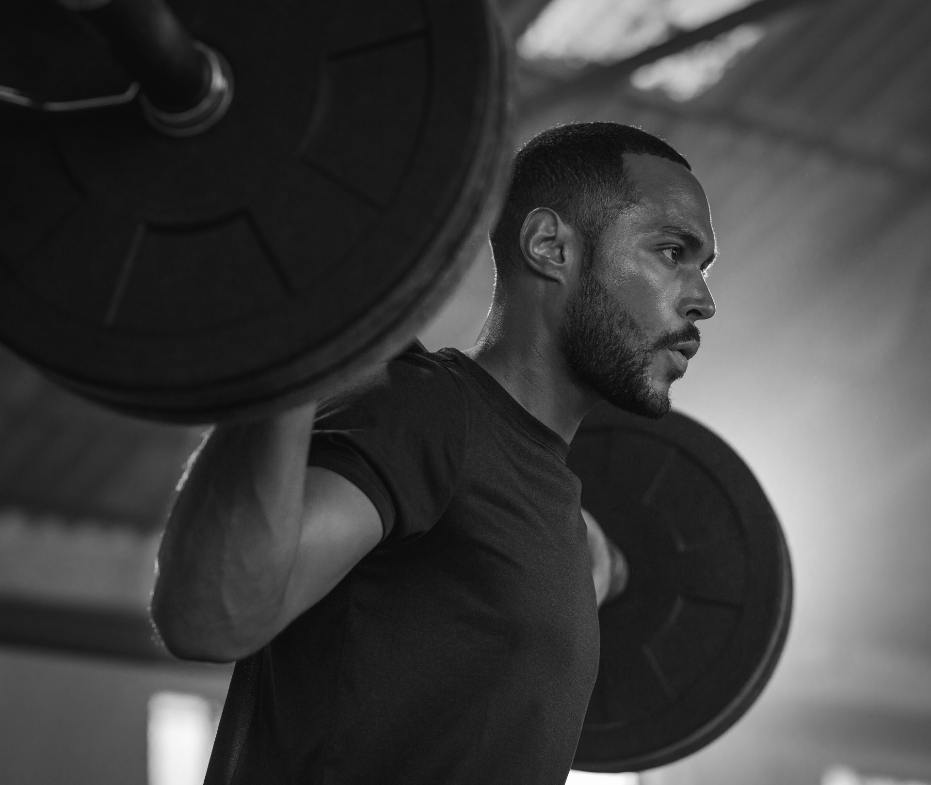 Mann mit Langhantel auf dem Rücken