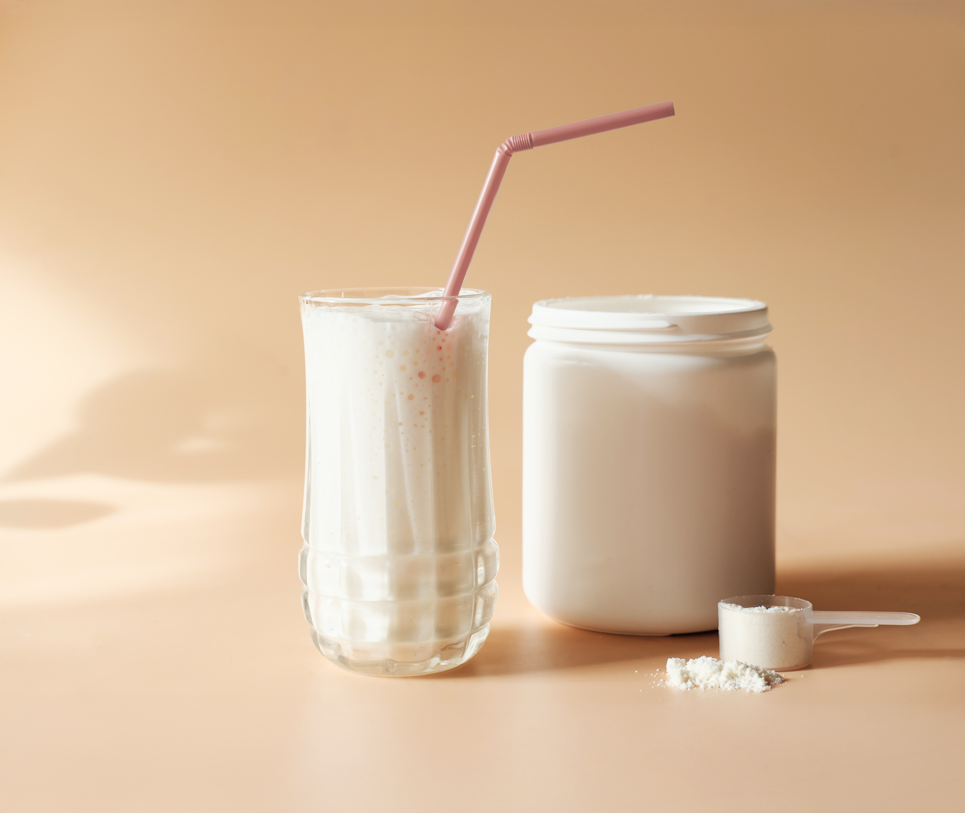 Proteinshake im Glas mit Strohhalm und mit der Dose daneben