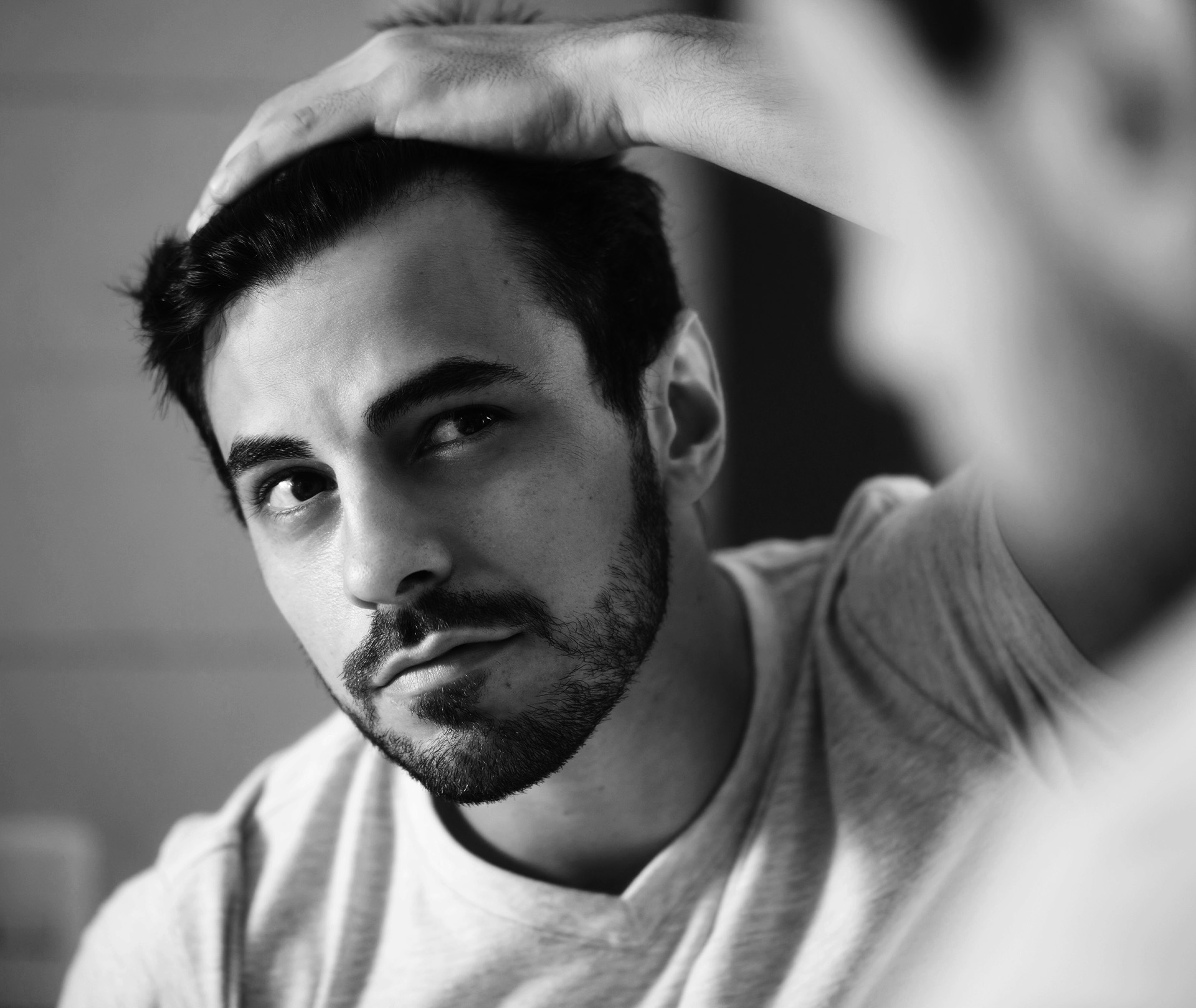 Mann schaut in den Spiegel nach seinen Geheimratsecken